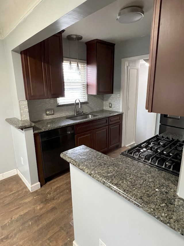 kitchen featuring dishwasher, dark stone countertops, sink, hanging light fixtures, and dark hardwood / wood-style flooring