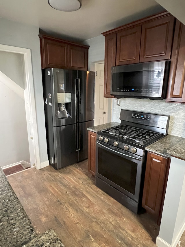 kitchen with decorative backsplash, appliances with stainless steel finishes, dark stone countertops, and light hardwood / wood-style floors