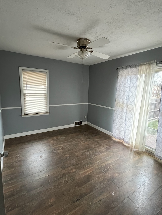 empty room with ceiling fan, a textured ceiling, and dark hardwood / wood-style floors