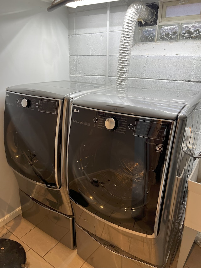 clothes washing area featuring light tile patterned floors and washing machine and clothes dryer