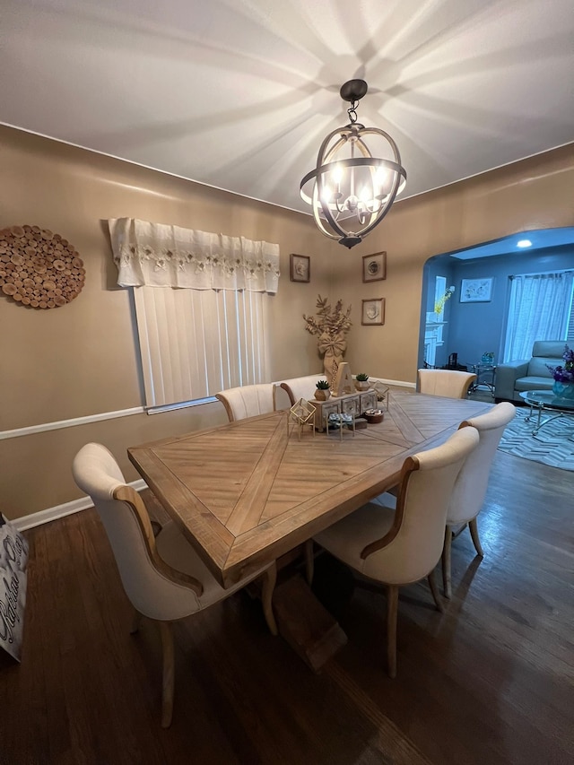 dining area featuring dark wood-type flooring and an inviting chandelier