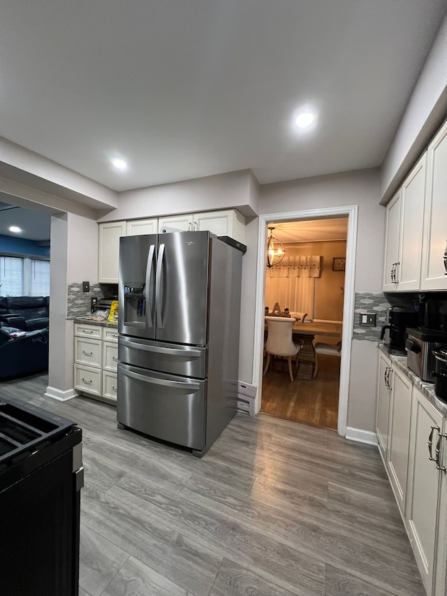 kitchen featuring stainless steel refrigerator with ice dispenser, hardwood / wood-style flooring, white cabinetry, and backsplash