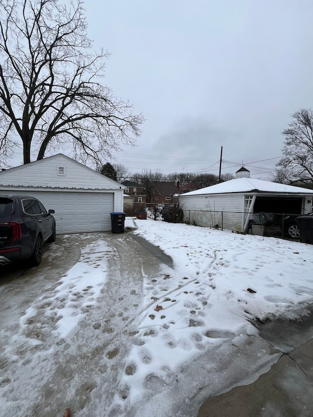 yard covered in snow with a garage and an outbuilding