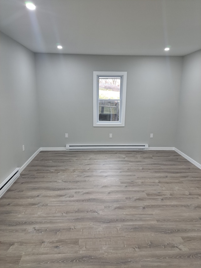 empty room featuring baseboard heating and light hardwood / wood-style flooring