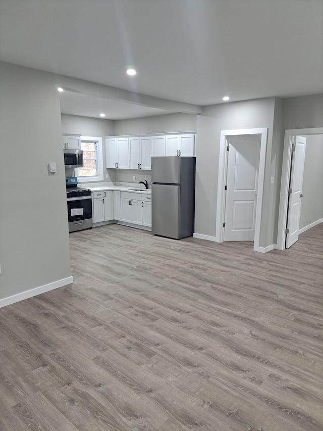 kitchen featuring light wood-type flooring, sink, stainless steel appliances, and white cabinetry