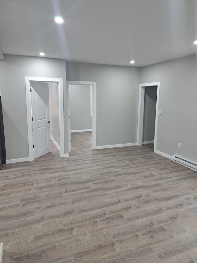 spare room featuring baseboard heating and light hardwood / wood-style floors