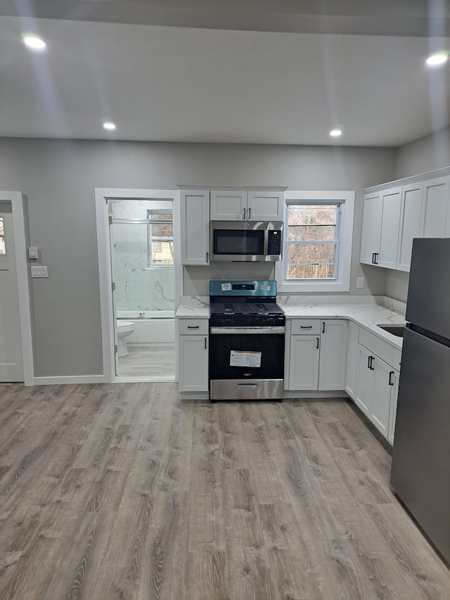 kitchen with plenty of natural light, stainless steel appliances, light hardwood / wood-style floors, and white cabinets