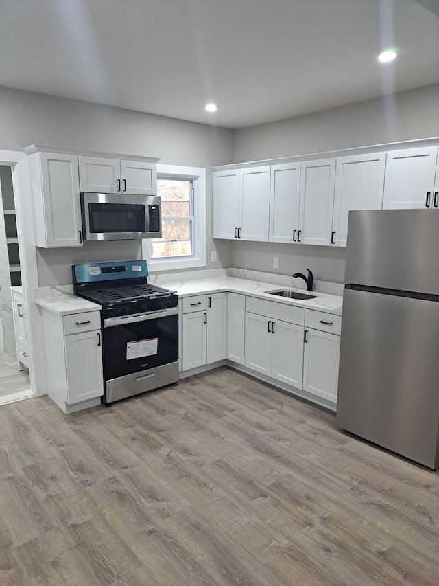 kitchen featuring white cabinets, sink, stainless steel appliances, and light hardwood / wood-style flooring