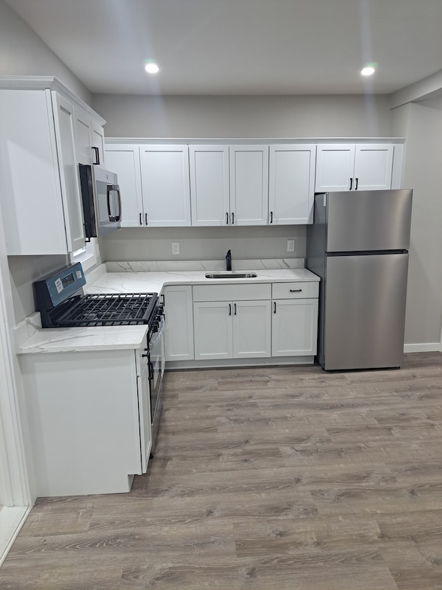 kitchen featuring white cabinets, sink, stainless steel appliances, and light hardwood / wood-style floors