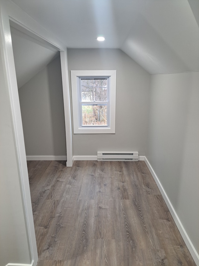 additional living space featuring a baseboard heating unit, lofted ceiling, and hardwood / wood-style flooring