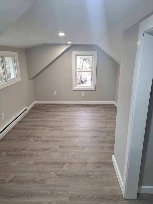 additional living space featuring lofted ceiling, baseboard heating, and light hardwood / wood-style flooring