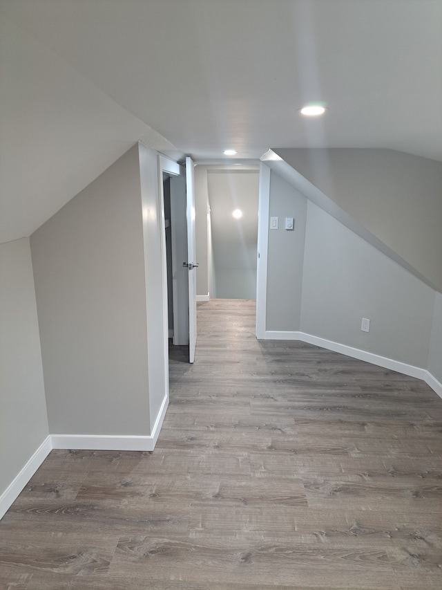 additional living space featuring light wood-type flooring and vaulted ceiling