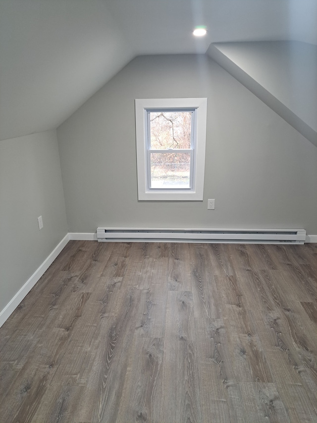 additional living space with a baseboard heating unit, lofted ceiling, and hardwood / wood-style floors