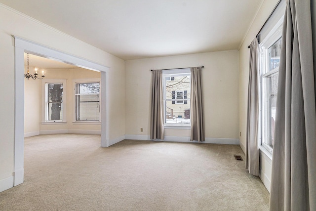 empty room with light carpet, a wealth of natural light, and a chandelier