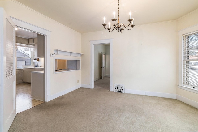 carpeted empty room featuring a chandelier and crown molding