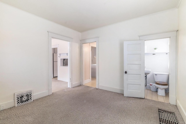 unfurnished bedroom featuring crown molding, light carpet, and ensuite bath