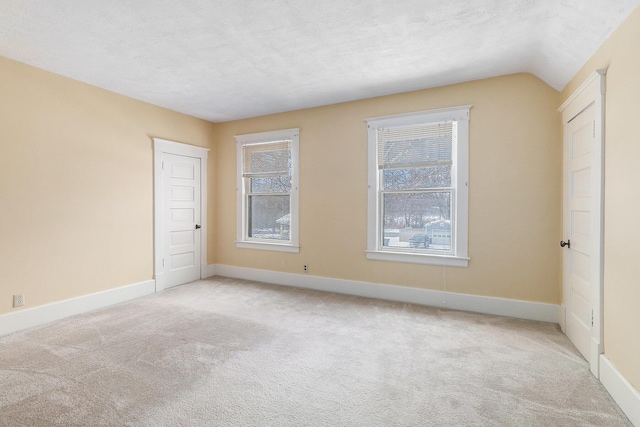 carpeted empty room featuring a textured ceiling and lofted ceiling