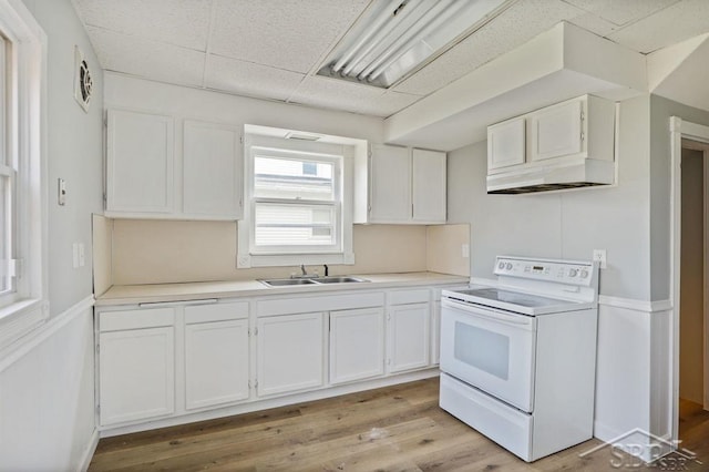 kitchen with white range with electric stovetop, sink, white cabinetry, light wood-type flooring, and a paneled ceiling