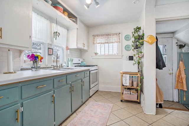 kitchen with sink, light tile patterned floors, gas range gas stove, and tasteful backsplash