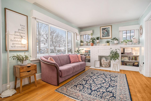 living room with light wood-type flooring, plenty of natural light, and a brick fireplace