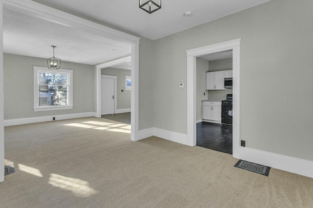 carpeted empty room featuring a notable chandelier