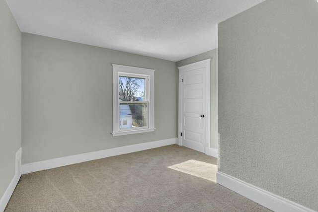 unfurnished room with carpet and a textured ceiling