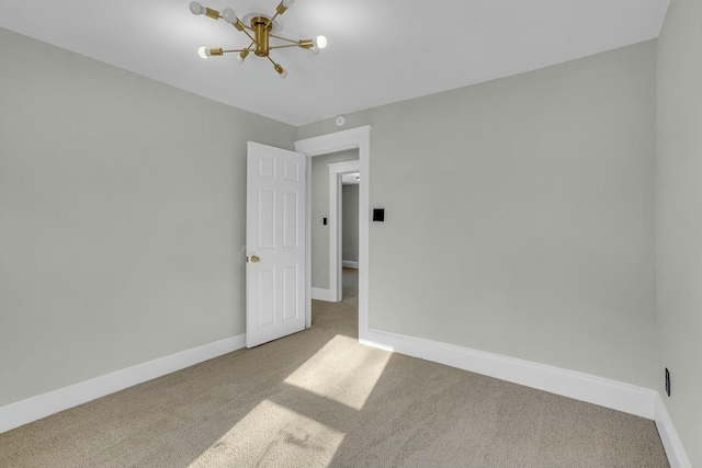 carpeted spare room featuring an inviting chandelier