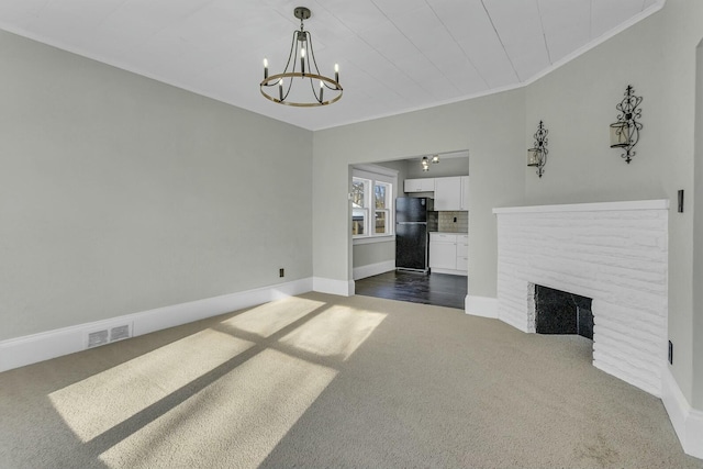 living room with dark colored carpet, a notable chandelier, crown molding, and a brick fireplace