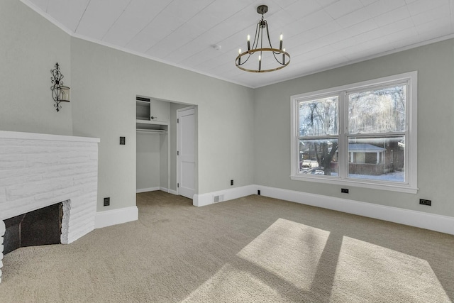 unfurnished living room with carpet, a stone fireplace, an inviting chandelier, and ornamental molding