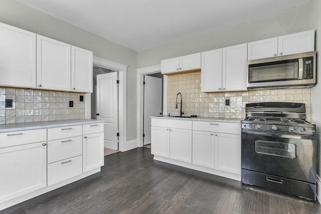 kitchen featuring decorative backsplash, sink, gas range, and white cabinetry