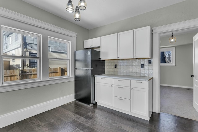 kitchen with black fridge, white cabinetry, tasteful backsplash, and decorative light fixtures