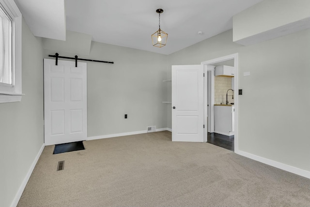 unfurnished bedroom featuring a barn door, carpet floors, and sink