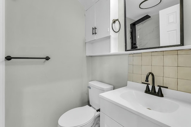 bathroom with toilet, vanity, and backsplash