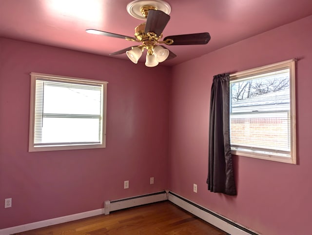 empty room featuring baseboard heating, ceiling fan, hardwood / wood-style floors, and a wealth of natural light