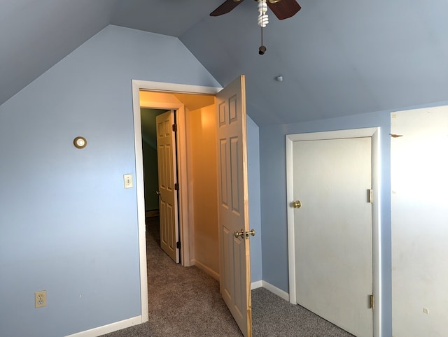 interior space with lofted ceiling, dark carpet, and ceiling fan