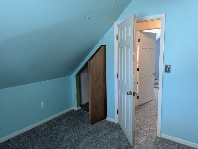 bonus room with dark carpet and vaulted ceiling