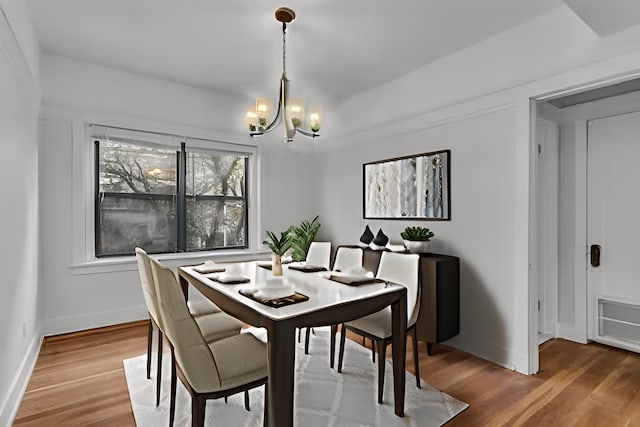 dining area featuring wood-type flooring and a chandelier