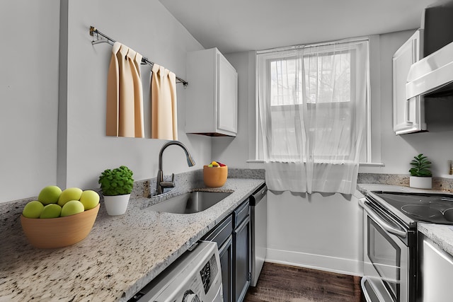 kitchen featuring light stone countertops, sink, wall chimney range hood, and white cabinets