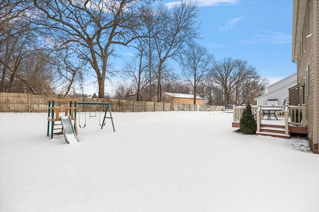 yard layered in snow featuring a playground