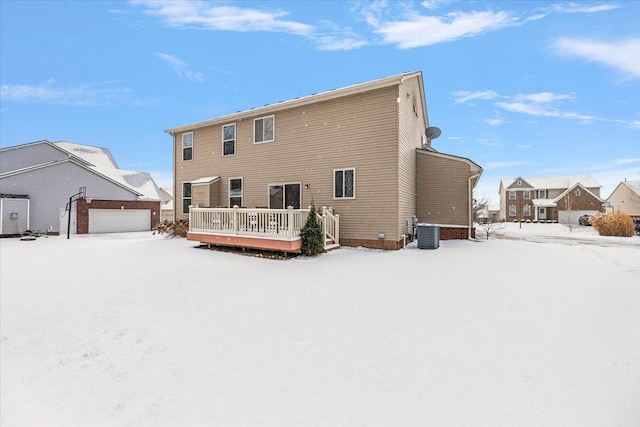 snow covered house with central AC unit and a wooden deck