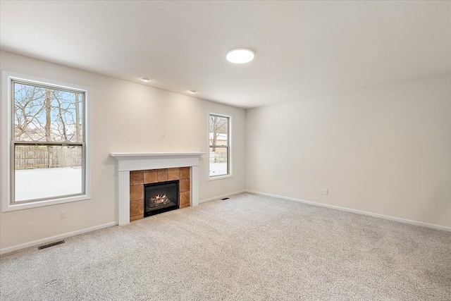 unfurnished living room with a tiled fireplace and carpet flooring