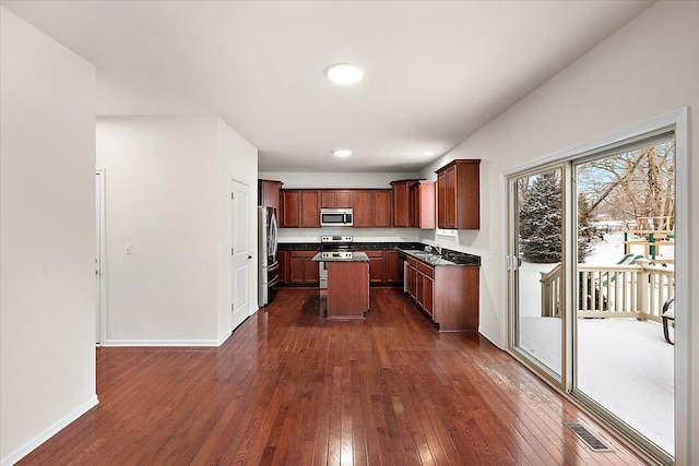 kitchen featuring dark wood-type flooring, sink, stainless steel appliances, and a center island