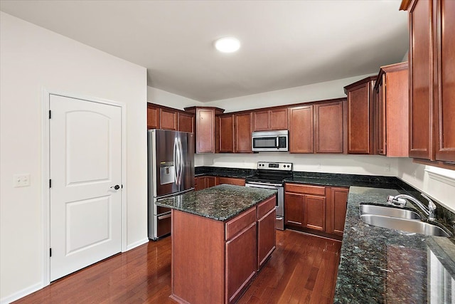 kitchen with dark stone countertops, a kitchen island, sink, appliances with stainless steel finishes, and dark hardwood / wood-style flooring