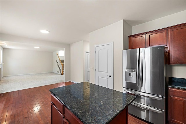 kitchen featuring stainless steel fridge, dark stone countertops, dark hardwood / wood-style flooring, and a kitchen island