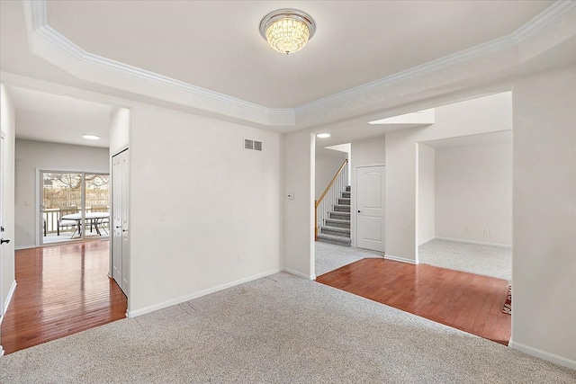 carpeted spare room with ornamental molding and a raised ceiling