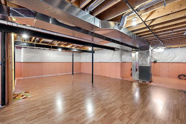 basement with hardwood / wood-style floors and heating unit