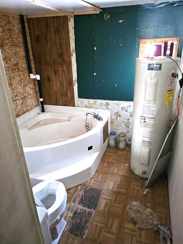 bathroom featuring a tub to relax in, toilet, and water heater