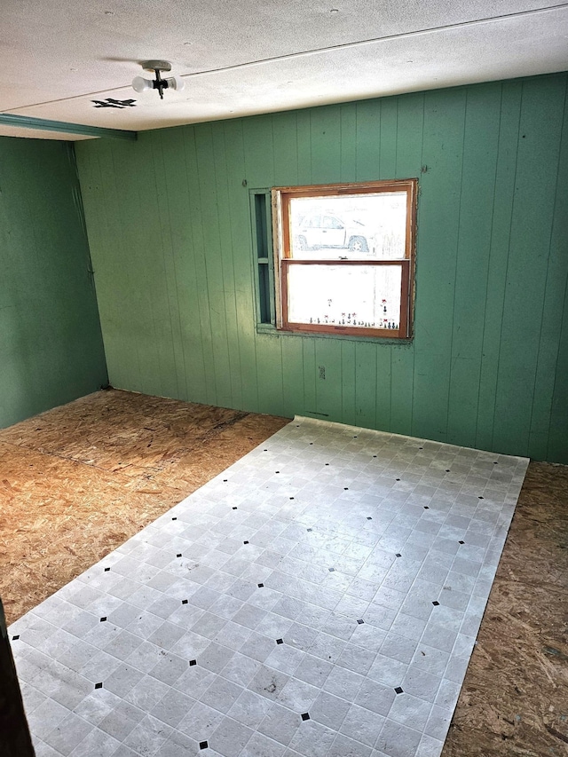 spare room featuring a textured ceiling and wood walls