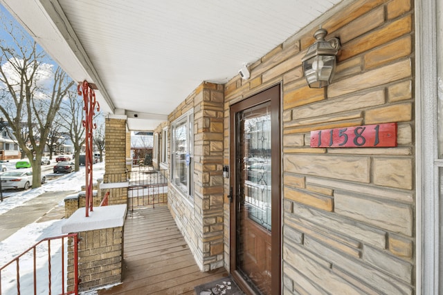 snow covered property entrance with stone siding