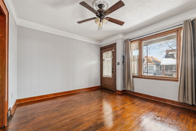 spare room featuring baseboards, a ceiling fan, dark wood-style flooring, crown molding, and a textured ceiling